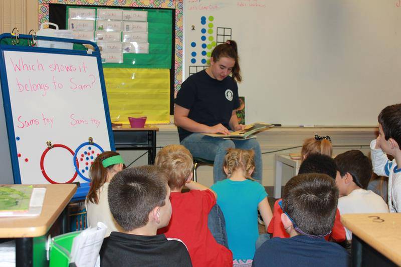 Bishop McGuiness High School student and St. Leo alum Caroline Deal read to 2nd grade St. Leo School students. (Photo provided Melissa Kinsley)