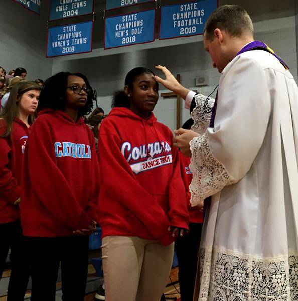 CHARLOTTE —Sophomore Jenai Johnson receives ashes from Father Jason Barone, Charlotte Catholic High School chaplain. Also pictured are fellow sophomores Candice Habton and Laney McBride. (Photo provided by Joann S. Keane)