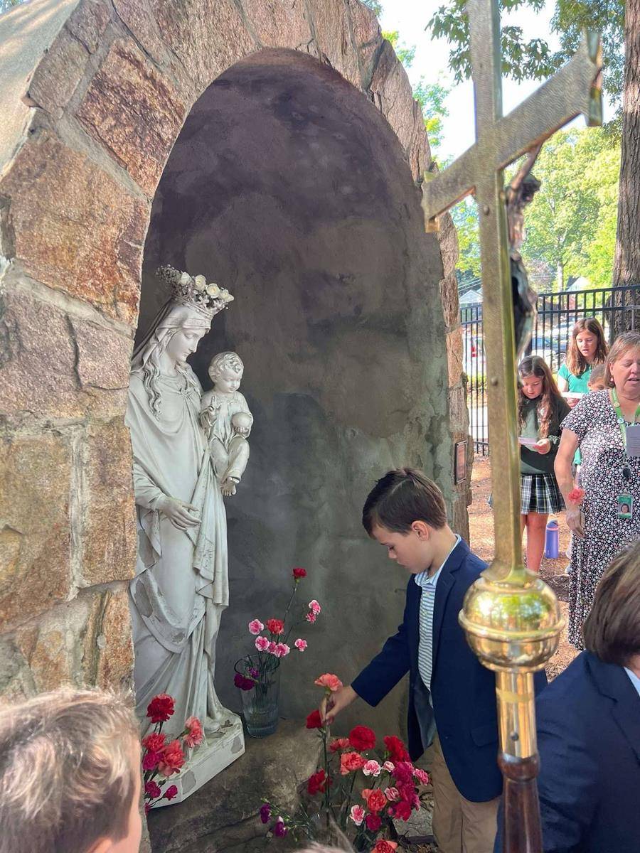 Second grade First Communicants lead processions during Mass and then afterwards to crown The Blessed Virgin Mary statue in our Marian Grotto.