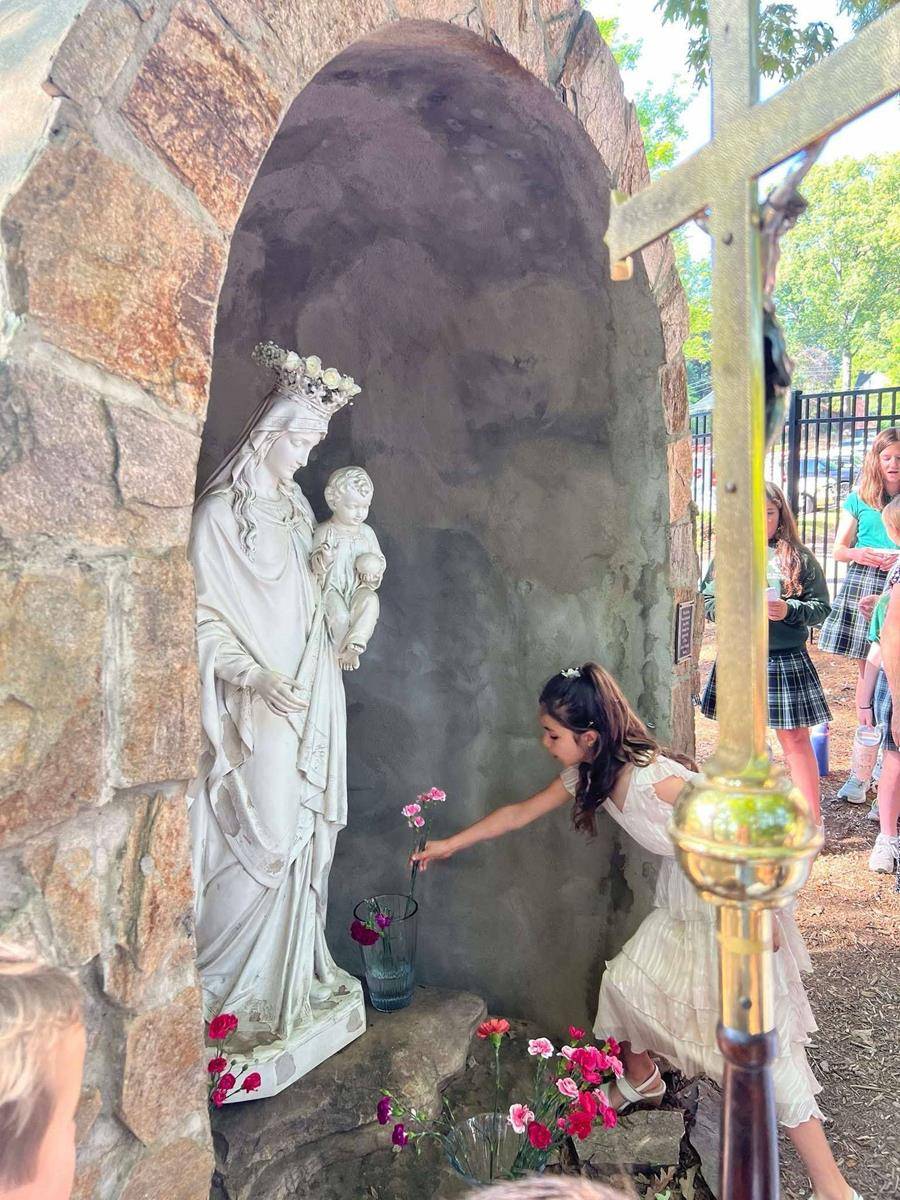 Second grade First Communicants lead processions during Mass and then afterwards to crown The Blessed Virgin Mary statue in our Marian Grotto.